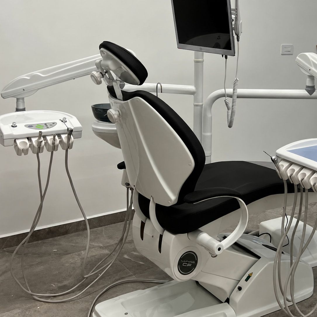 Sillón dental blanco y negro del consultorio EndoBIO, con monitor y bandejas de instrumental